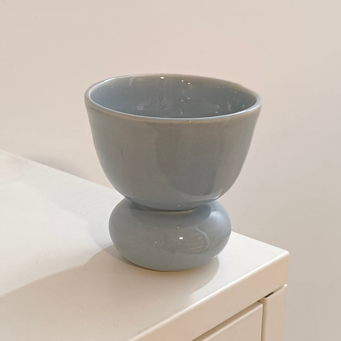 A light blue ceramic pedestal cup with a glossy finish